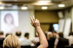 Raised fingers in classroom at university.